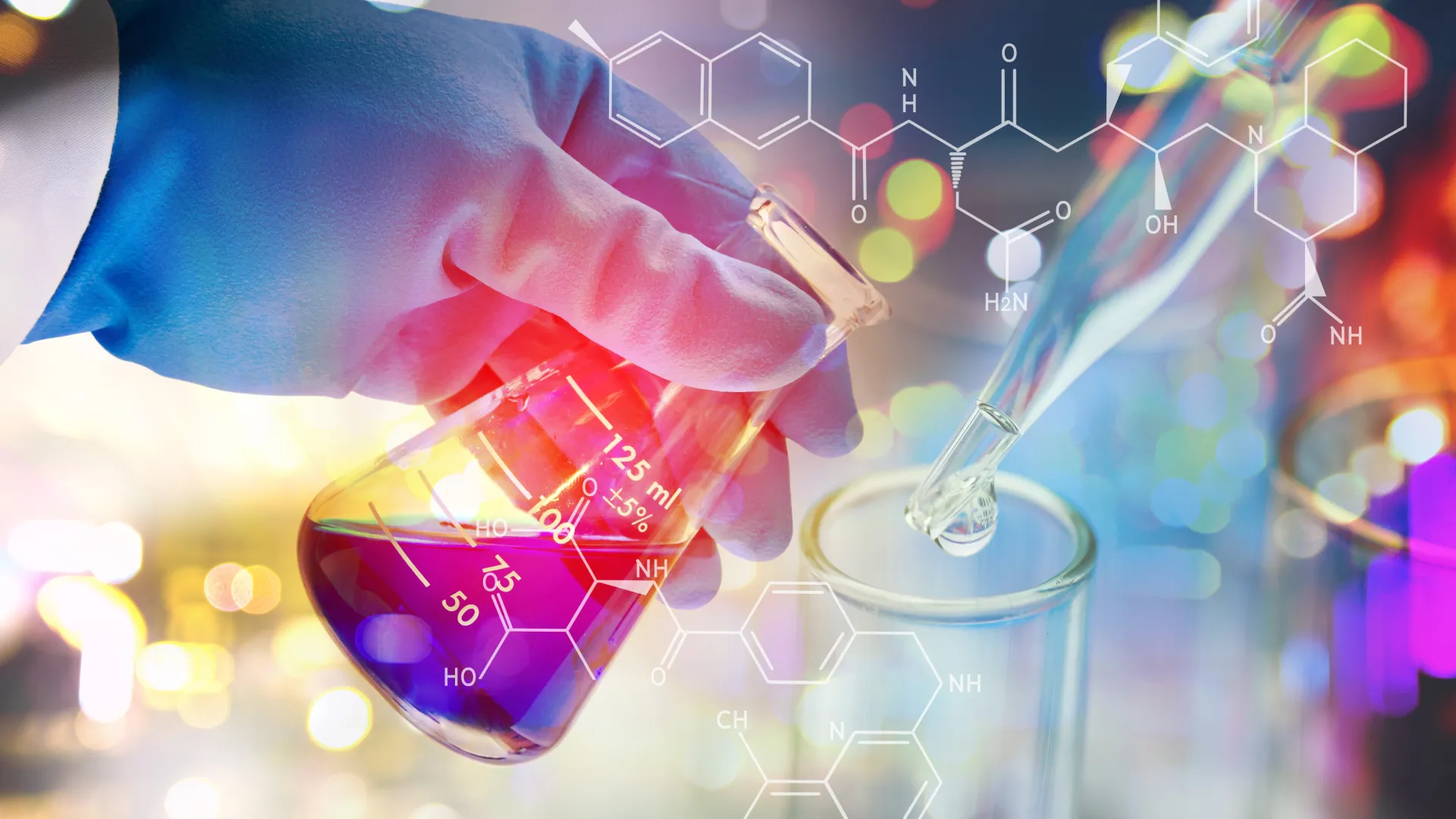Behandschuhte Hand im Labor mit Pipette und Laborgefäßen